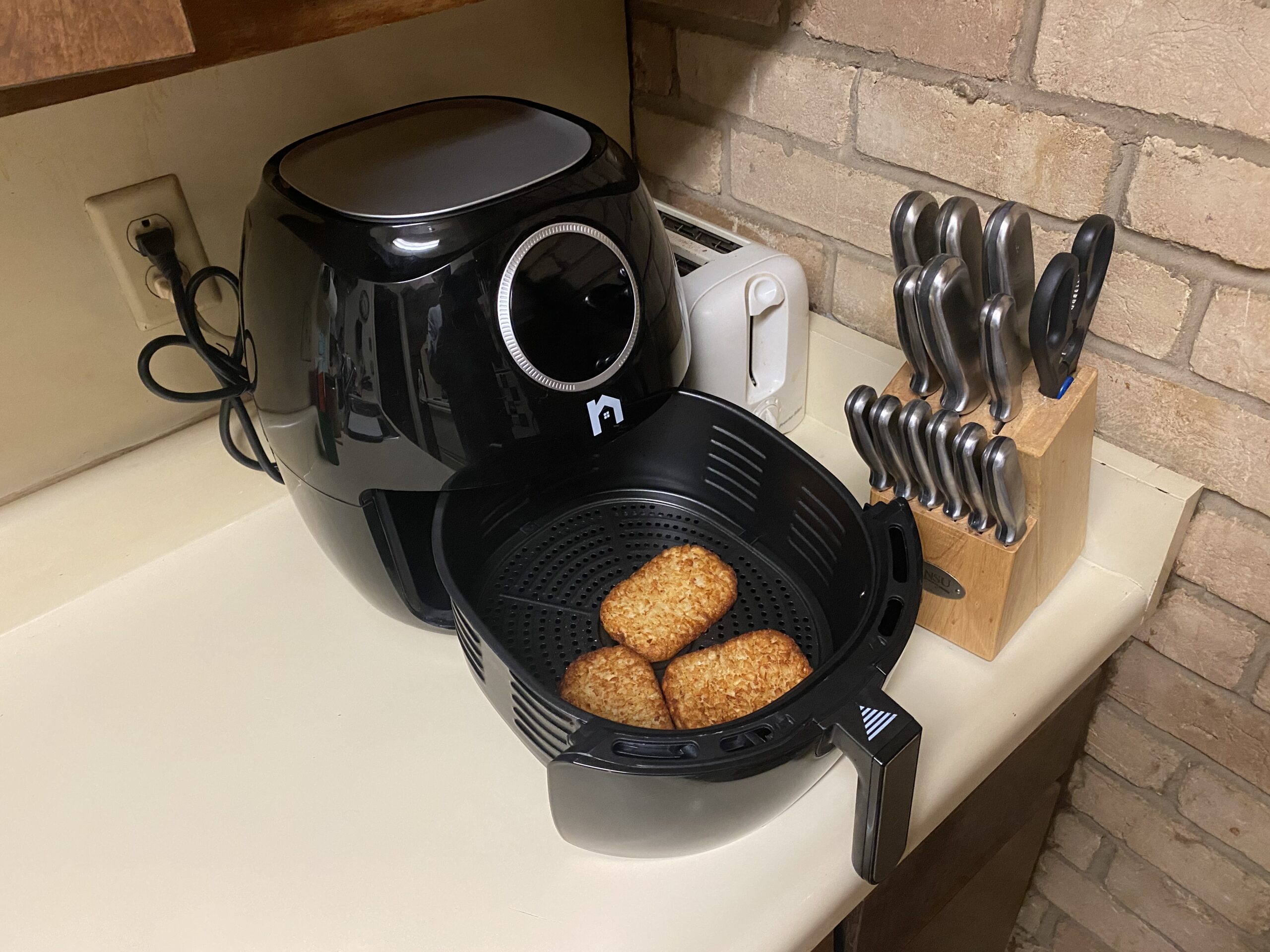 Air fryer on a kitchen counter with crispy food inside